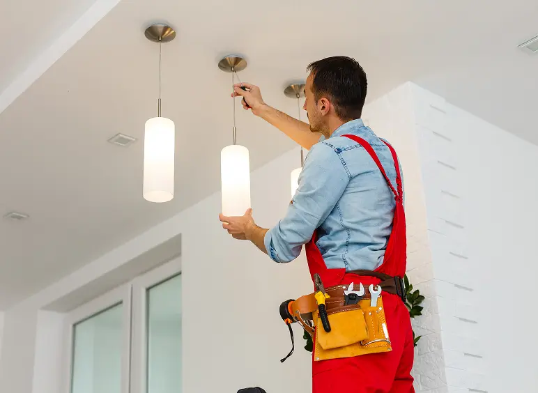 Electrician fixing ceiling light fixture