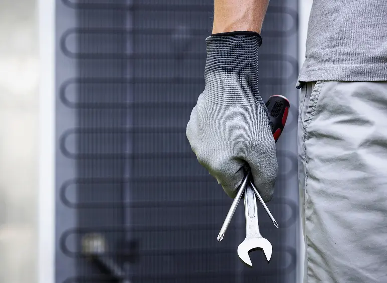 Gloved hand holding wrench and screwdriver