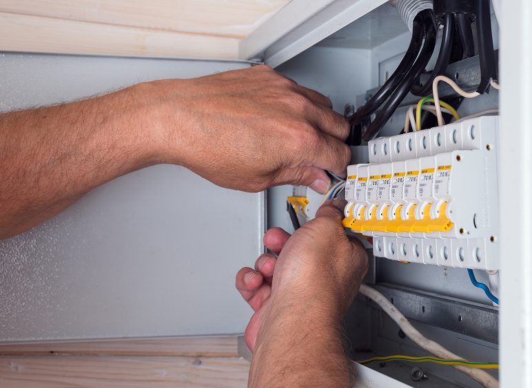 Hands adjusting electrical panel wiring