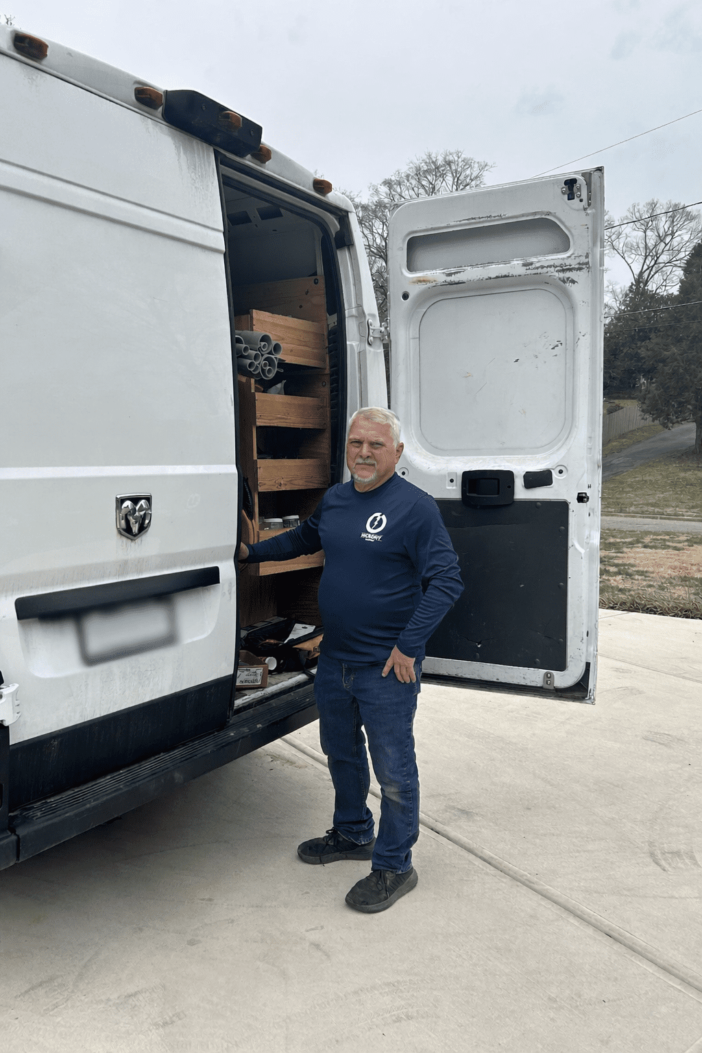 Man standing by an open delivery van filled with packages.